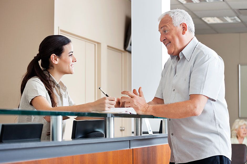 Improving Patient Satisfaction - Patient Talks to Receptionist at Check-in Desk
