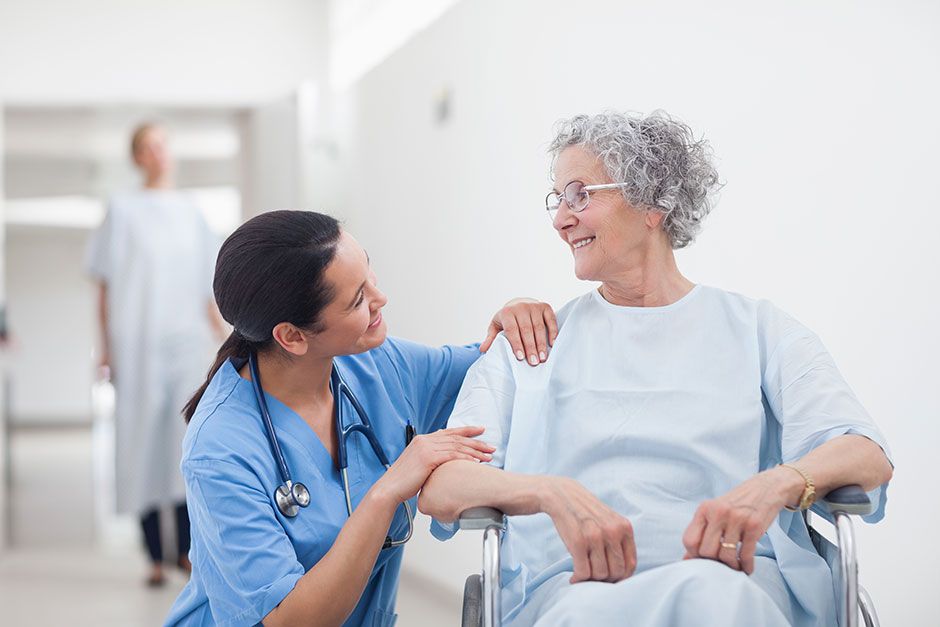 Is There a Nursing Shortage? | Nurse Kneeling Down Talking to Patient in Wheelchair